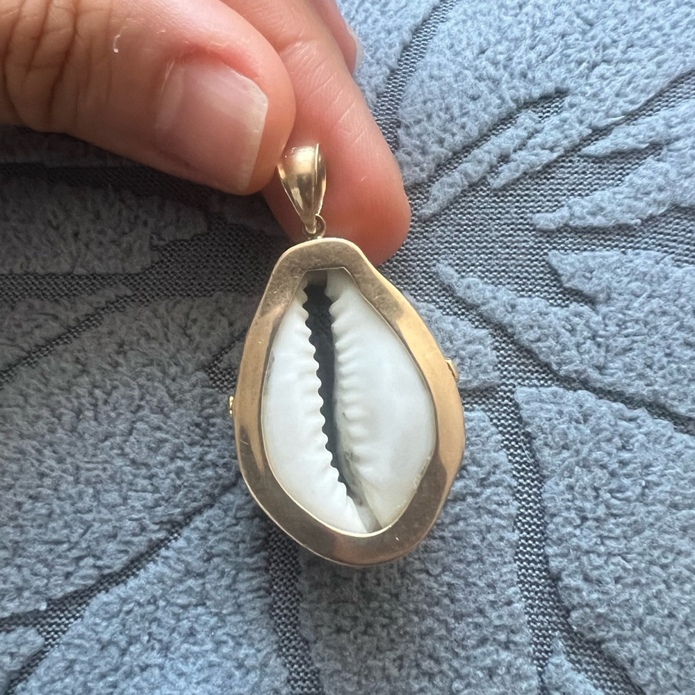 A pendant with a cowrie shell framed in 14K gold is a piece
